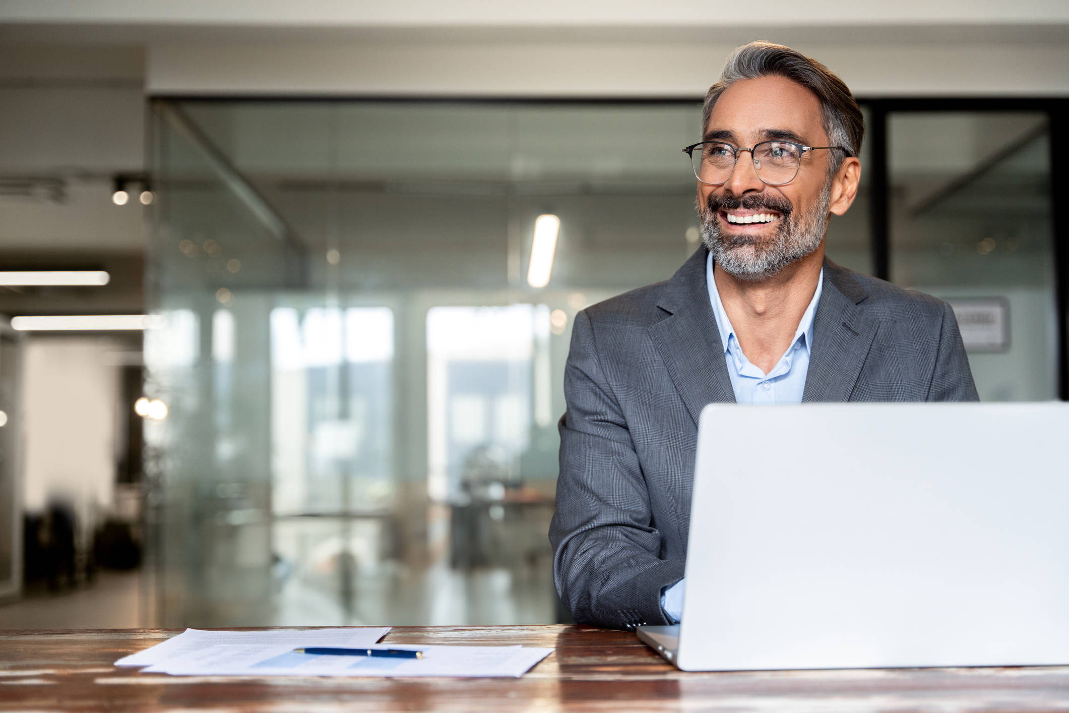 Professional Hispanic male smiles while seated in his office