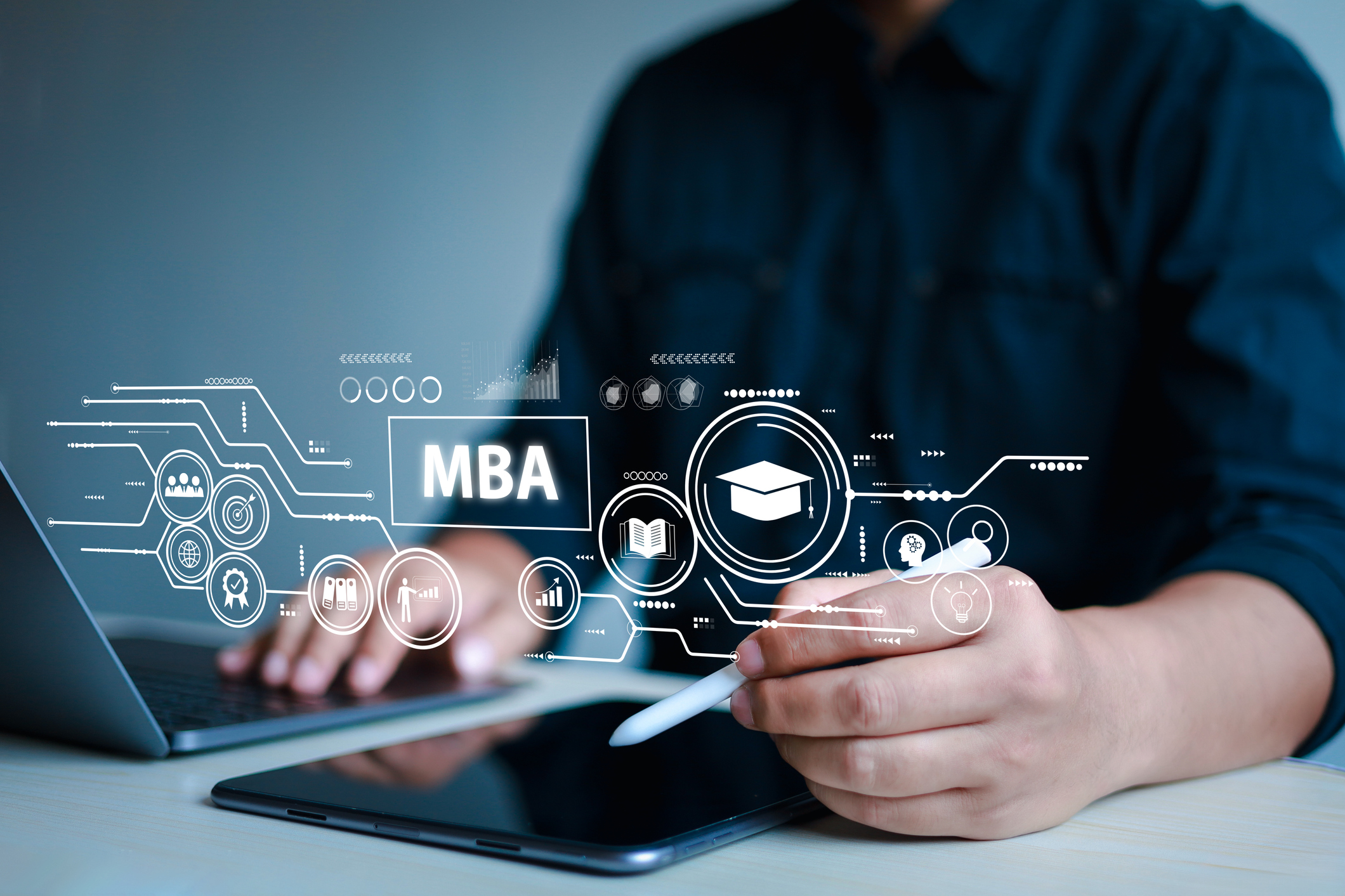 mba icons hover in front of a male student's stylus, tablet and laptop