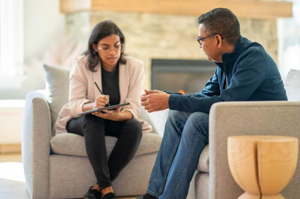 A therapist takes notes while talking with a client.