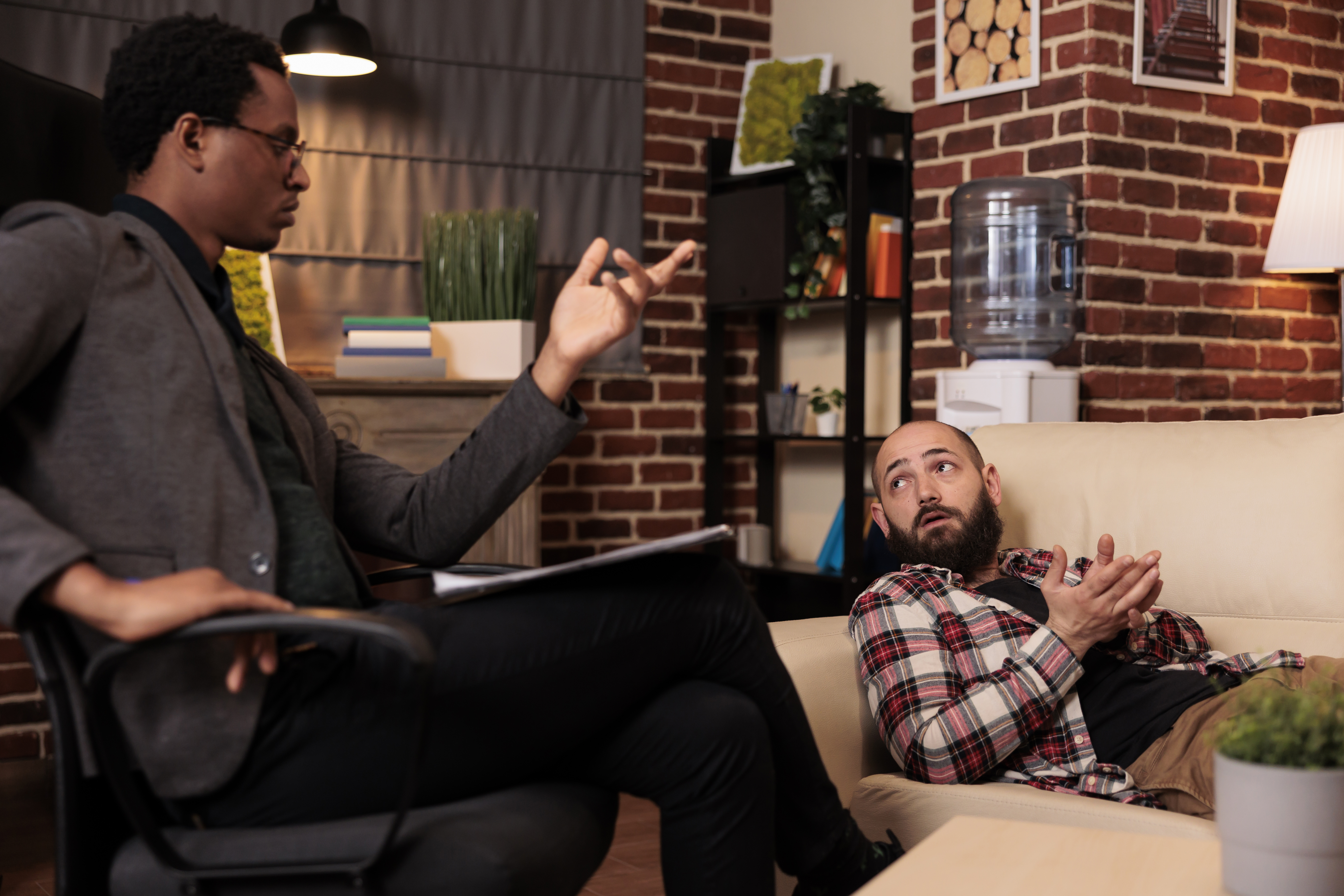 A Hispanic mental health professional listening to a caucasian patient