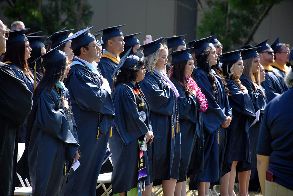 Students in caps and gowns standing at graduation.