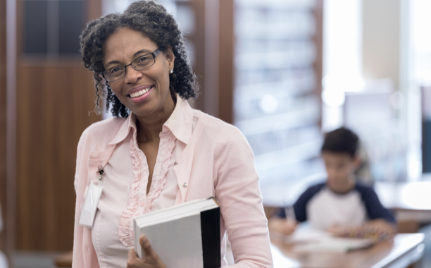 person standing and smiling while holding a book