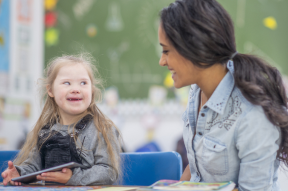 Teacher and a student in a classroom looking at each other. 